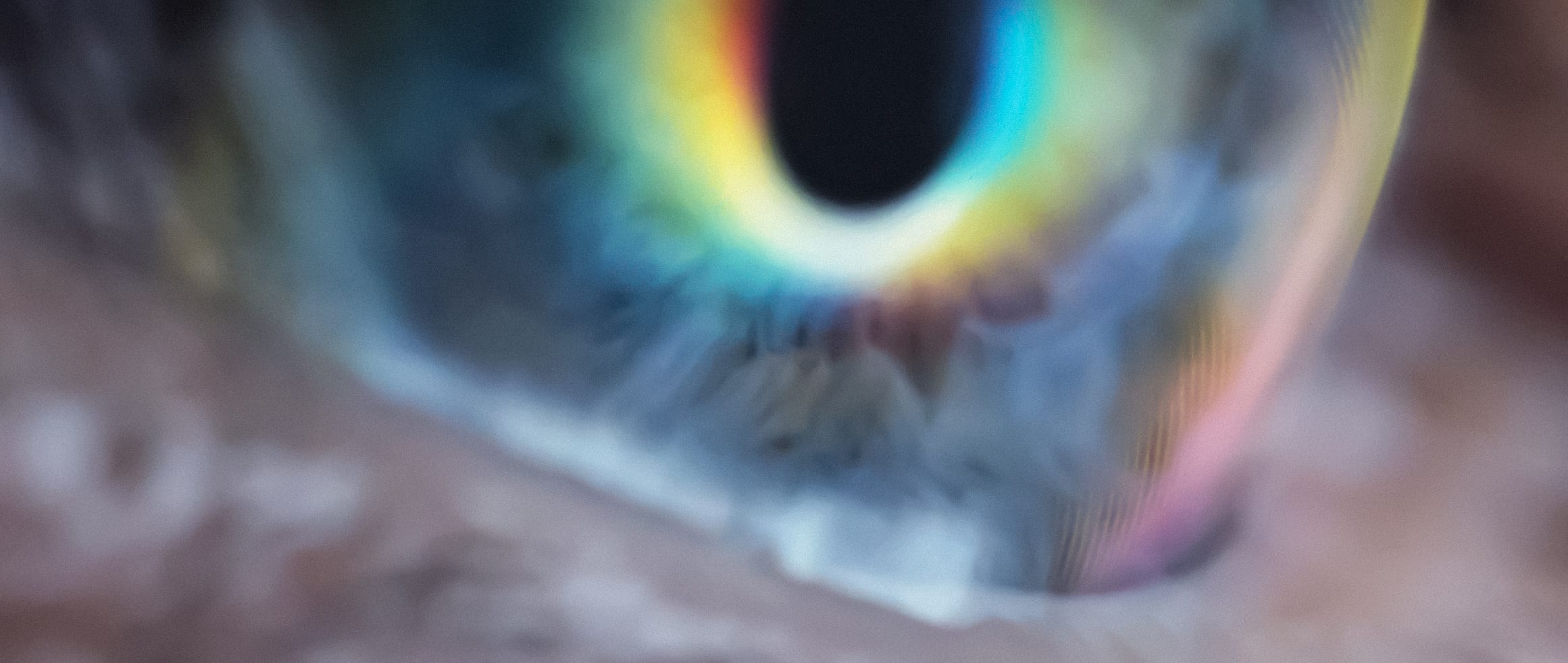 Extreme close-up of an eye refracted by blue, yellow and pink augmented-reality light