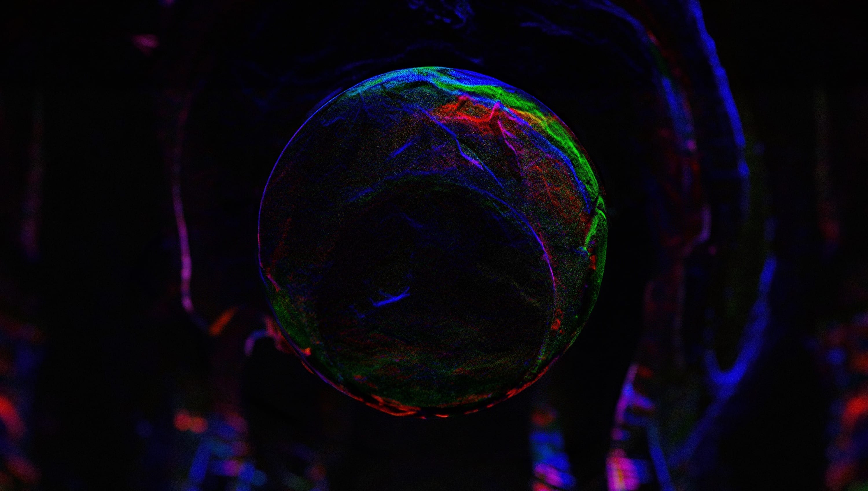 A dark chromatic orb suspended within a granular blue, green and magenta environment