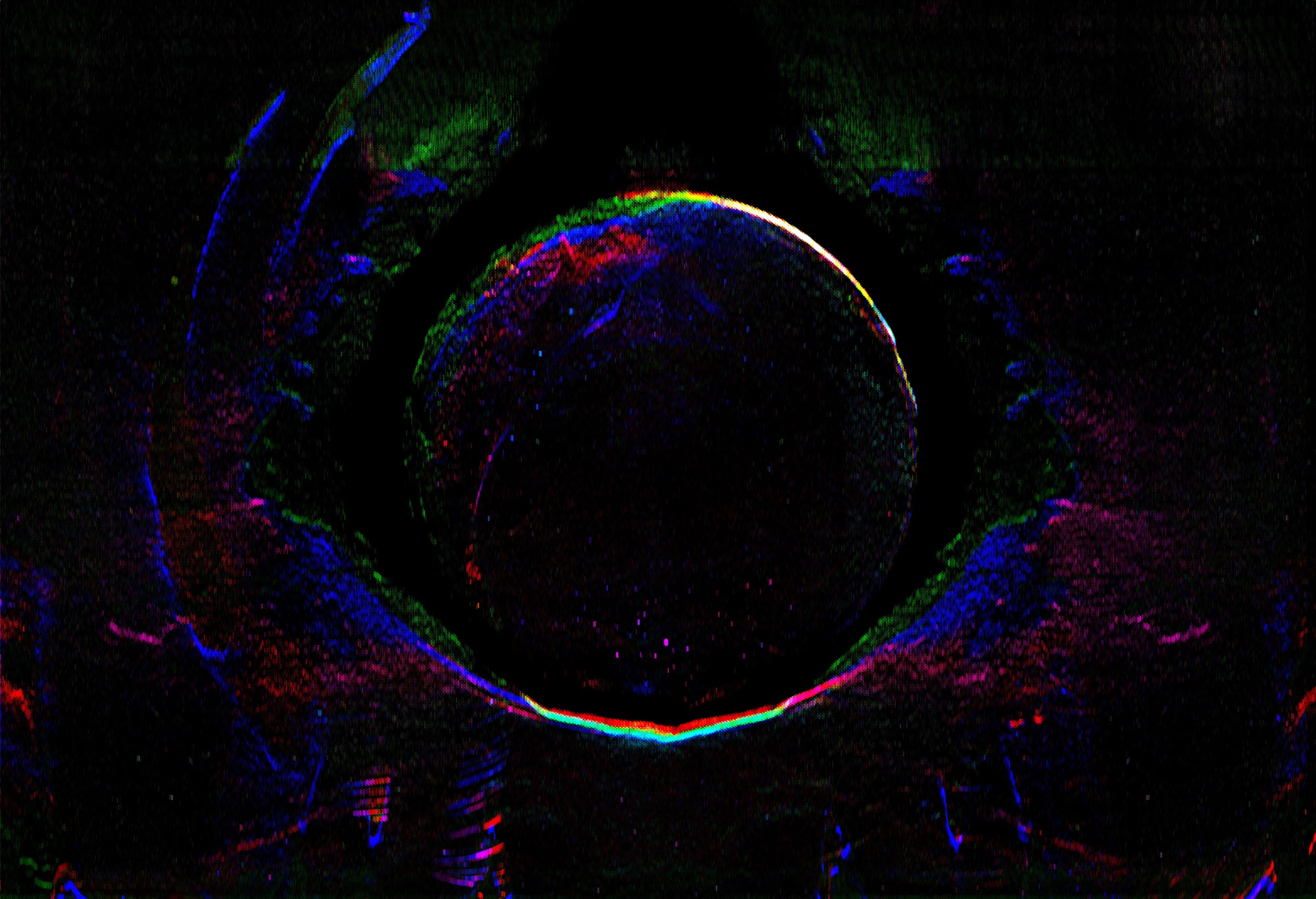 A detailed neon organic aperture opening within a black field
